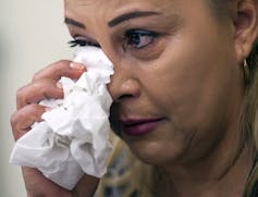 Une femme pleure dans une poignée de mouchoirs