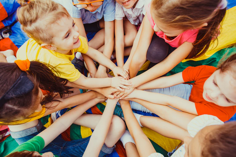 Un groupe d'enfants et vu de haut, avec un gros plan sur leurs mains qui se rejoignent