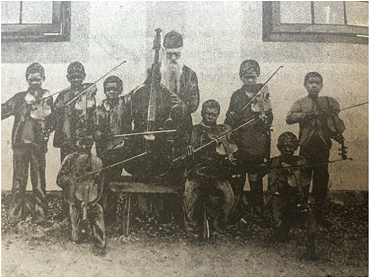 8 young Aboriginal boys with violins, a bearded man with a cello.