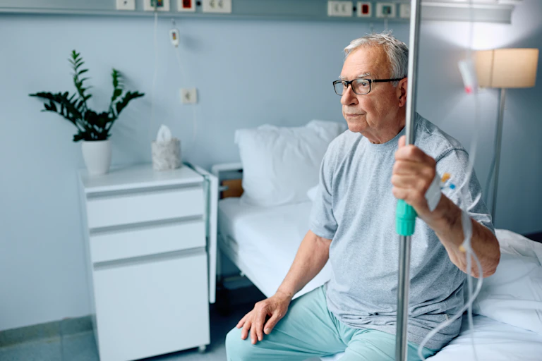 A senior man sitting on a hospital bed.