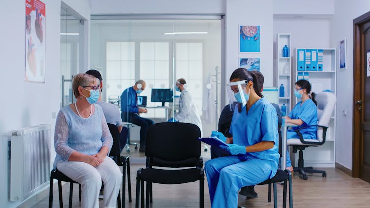 A number of patients and staff in a healthcare setting wearing masks.