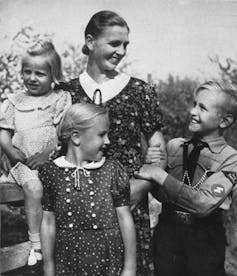 Fotografía de una mujer rubia rodeada de tres niños pequeños también rubios.