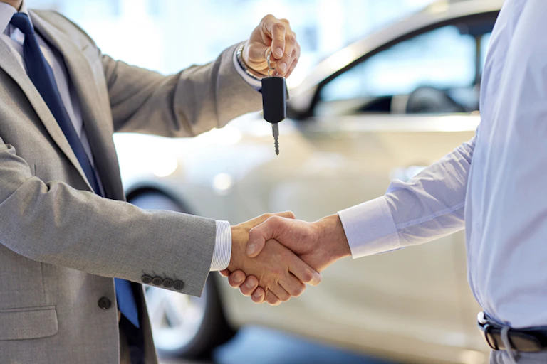 Un vendeur de véhicule conclut une vente.