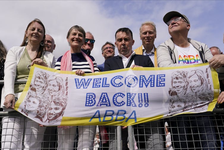 People seen holding a banner that says 'welcome back ABBA.'