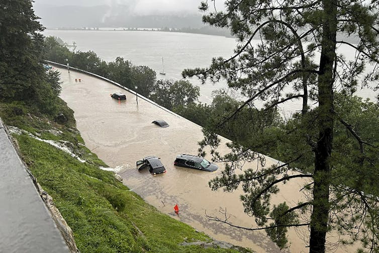 Extreme rainfall flooded streets along the Hudson River, which is in the background. Water still pours down a hillside.