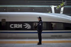 A train speeds by a man dressed in a police uniform