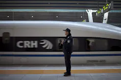 A train speeds by a man dressed in a police uniform