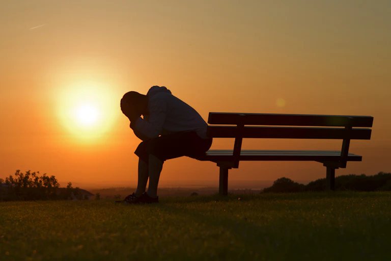 Person silhouetted sitting on outdoor bench