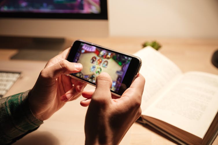 A photo of a person's hands holding a phone and playing a game.
