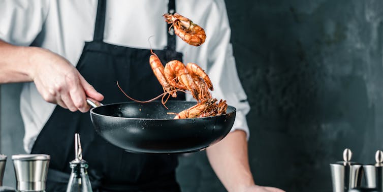 Chef salteando unas gambas en la sarten