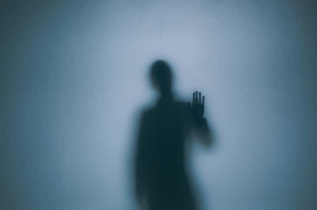 A silhouette figure surrounded by fog reaches out with his left hand.