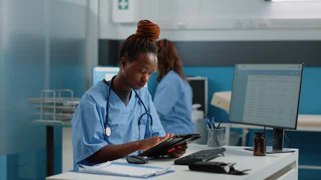 A nurse using a tablet at a desk.