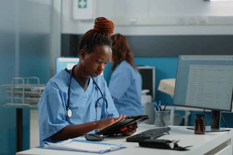 A nurse using a tablet at a desk.