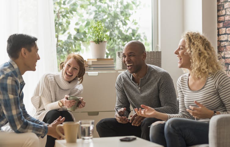 Four people in a living room, laughing and talking.