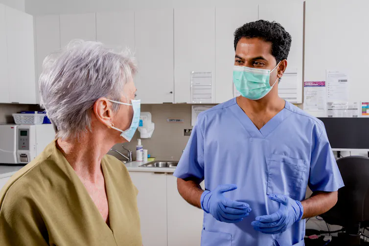 A male nurse of Indian appearance with a senior female patient.