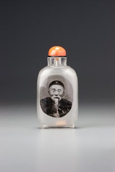 A small snuff bottle with the portrait of a Chinese man on the side.