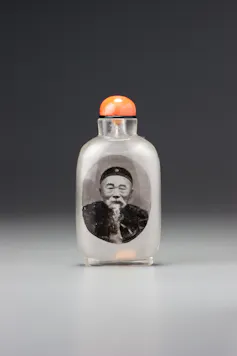A small snuff bottle with the portrait of a Chinese man on the side.