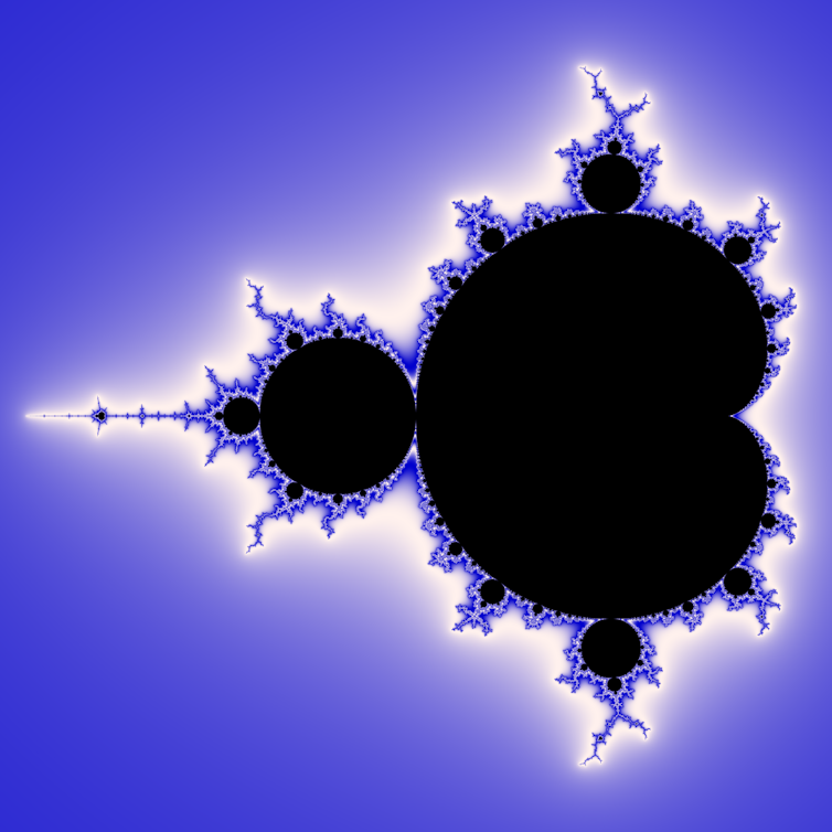 The Mandelbrot set, a mathematical fractal, shown in black against a blue background. The edges of the fractal are blue and white
