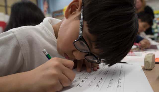 a student seen with pencil practising cursive.