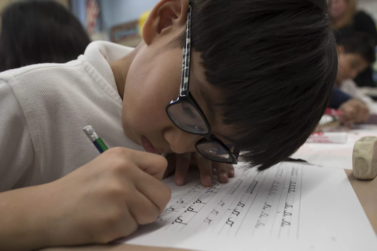a student seen with pencil practising cursive.