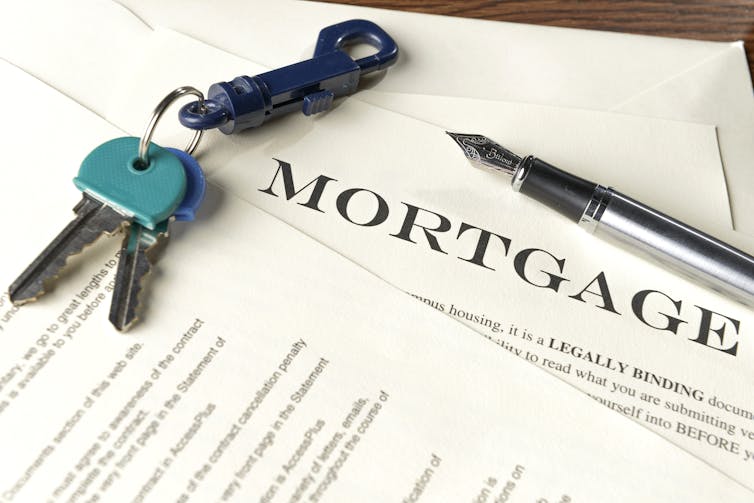 A pair of keys and a fountain pen sitting on top of mortgage papers