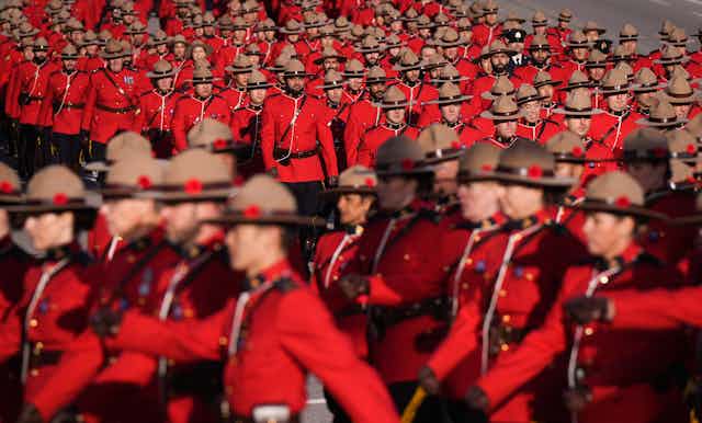A sea of Mountie in red serge coats and brown stetson hats march