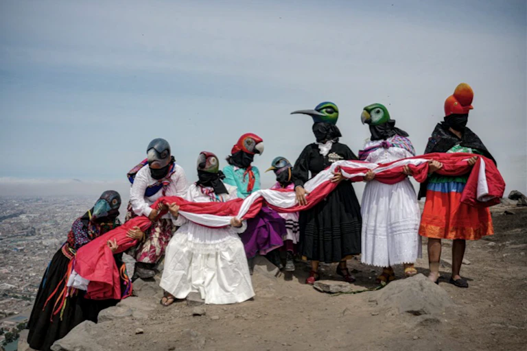 Une dizaine de personnes en masques représentenat des oiseaux sur une montagne