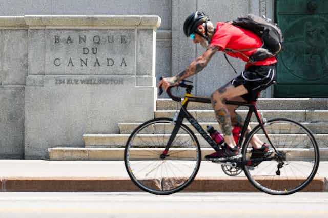 Person on bike cycles past Bank of Canada building