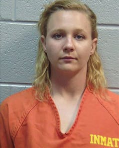 A blond-haired woman in an orange shirt with 'INMATE' printed on it.