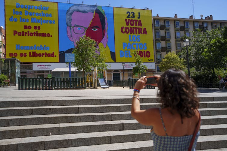 A woman takes a pictures of a political banner