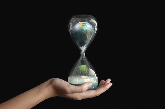 The planet Earth inside an hourglass in human hand