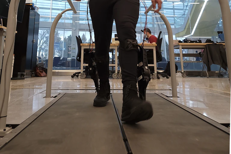 A person walks while wearing an ankle exoskeleton on a treadmill