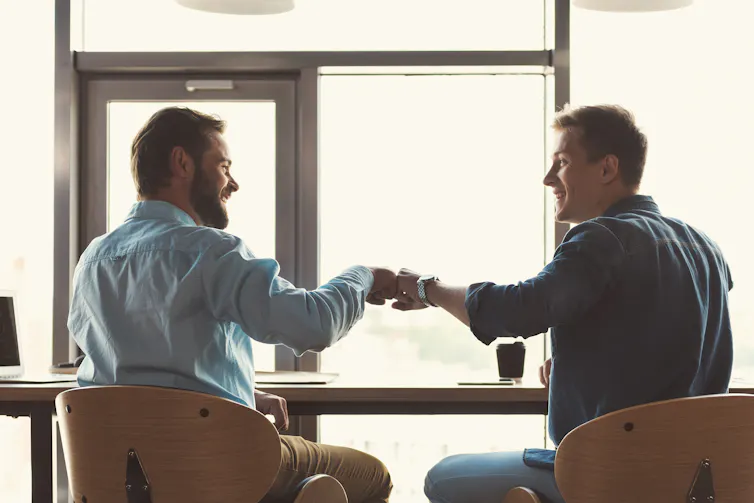 Deux hommes tenue d’affaire décontractée se montrent amical l’un vers l’autre en prenant un café