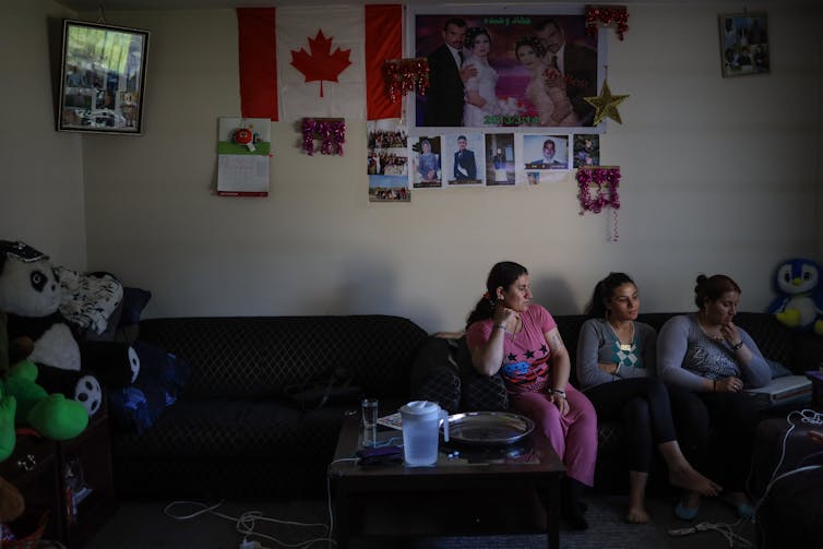 Three women on a sofa in a room with a Canadian flag on the wall