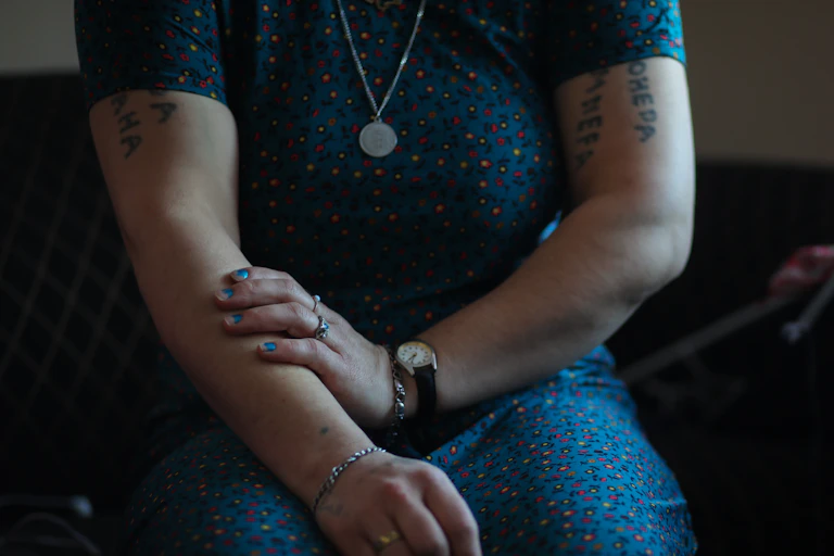Cropped image of a woman in a blue dress with tattoos on her arms