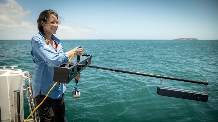 PhD candidate Andrea López onboard a boat deploys a baited remote underwater video systems rig