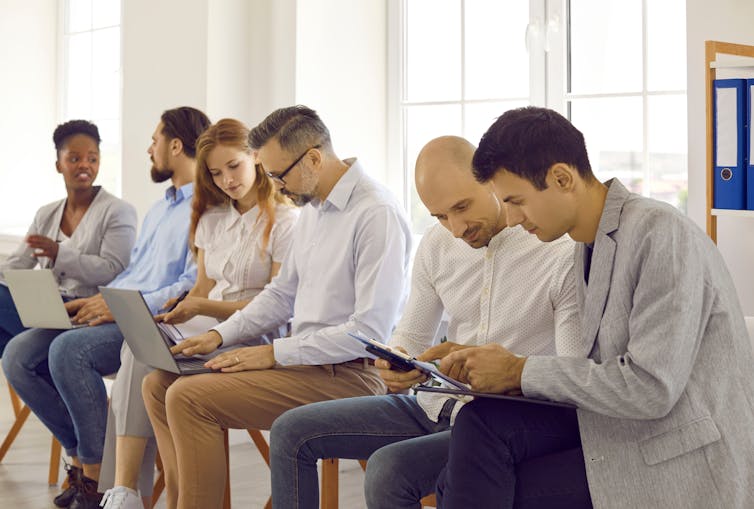 Business people on seminar training discussing in pairs making tasks together using laptops.