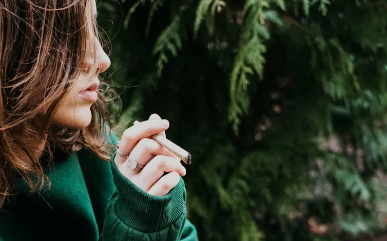 Photo d’une adolescente avec un joint de cannabis à la main.