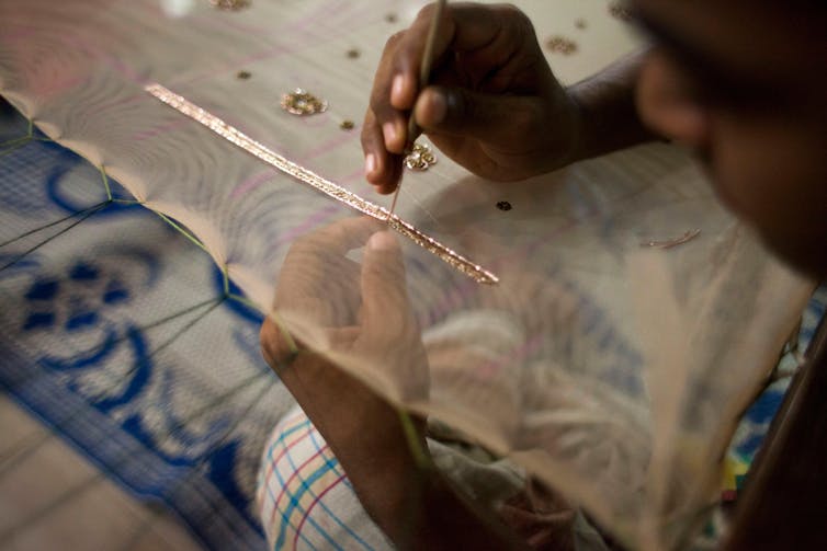 A garment industry worker working on a hand-embroidery frame.
