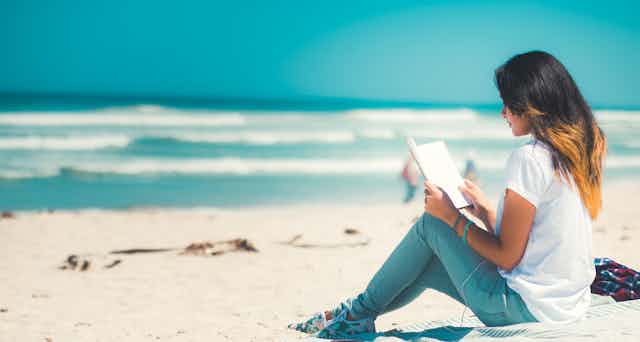 Woman sitting at the beach reading.