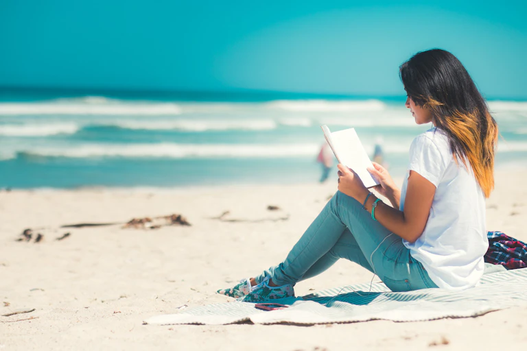 Woman sitting at the beach reading.