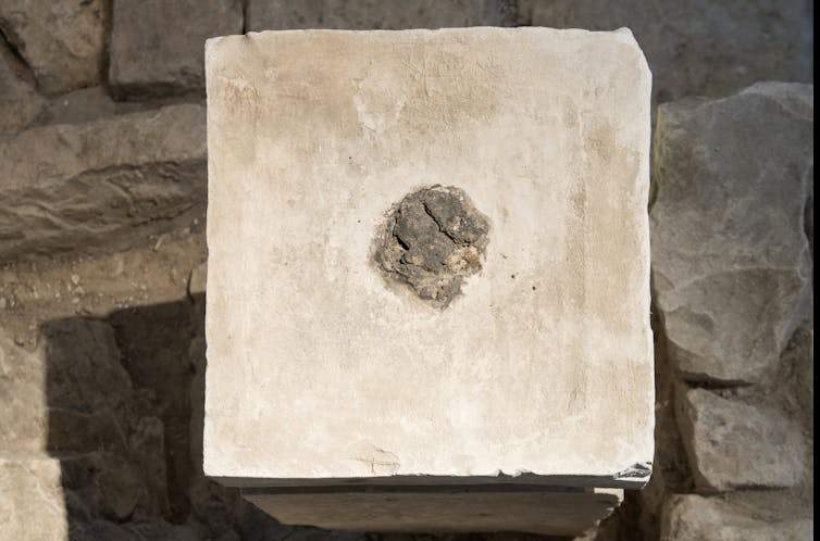 A square stone block appears to have hardened remnants of a darker substance in the middle of it.