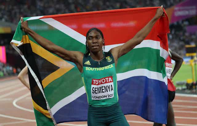 Female athlete holding up South African flag. 