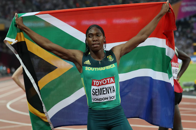 Female athlete holding up South African flag.