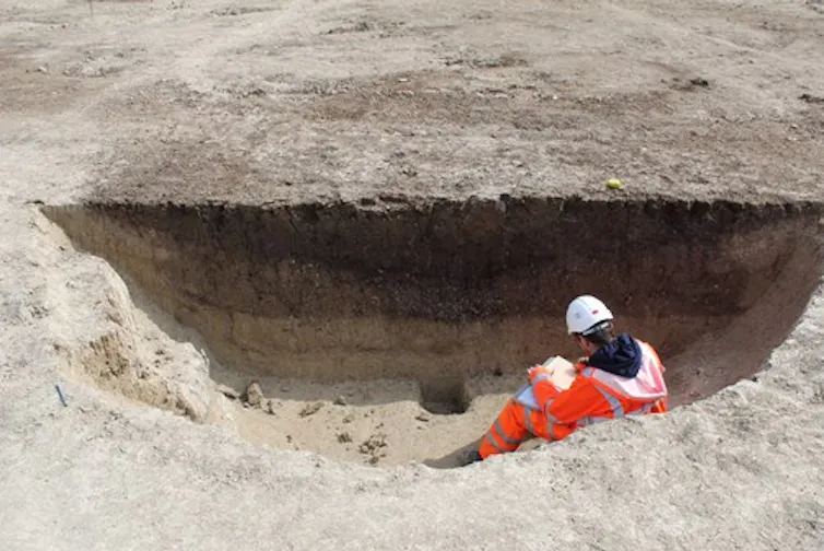 A man in a high vis jacket and hard hat sat in a pit.