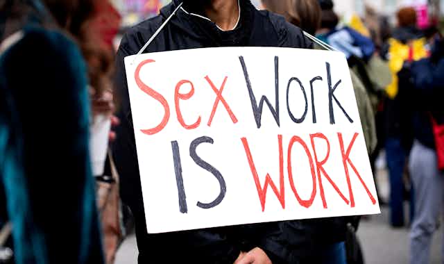 A person at a protest carried a placard that reads: Sex work is work