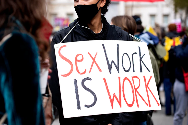 A person at a protest carried a placard that reads: Sex work is work