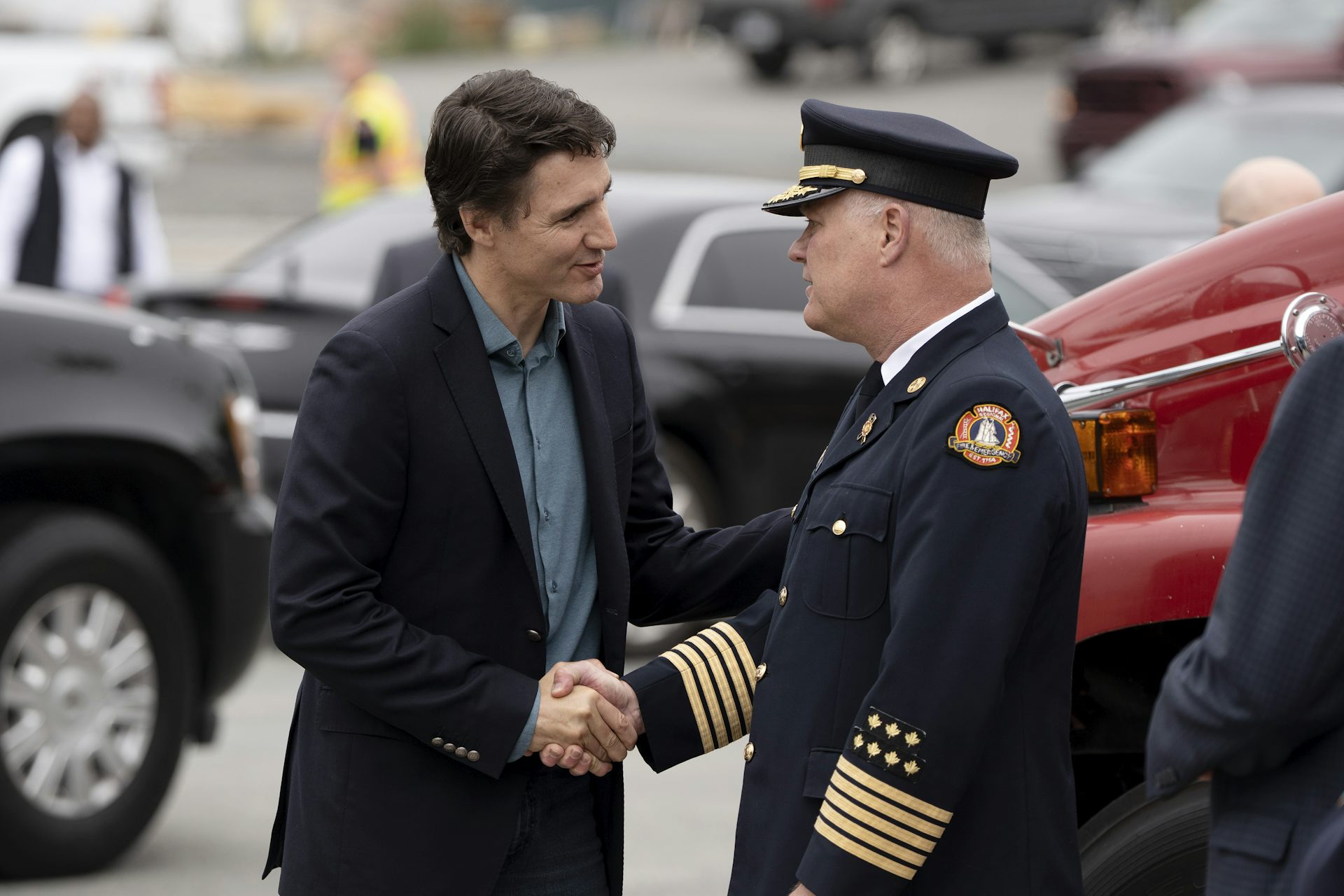 A man in a suit shakes the hand of a man in a fire chief's uniform.