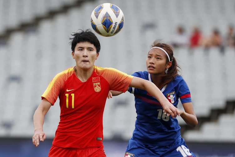 Soccer player Wang Shanshan, left, of China, left, goes up for a header against Taiwan's Li Pei-Jung