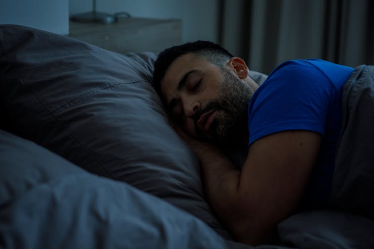 A man is sleeping in a dark room.